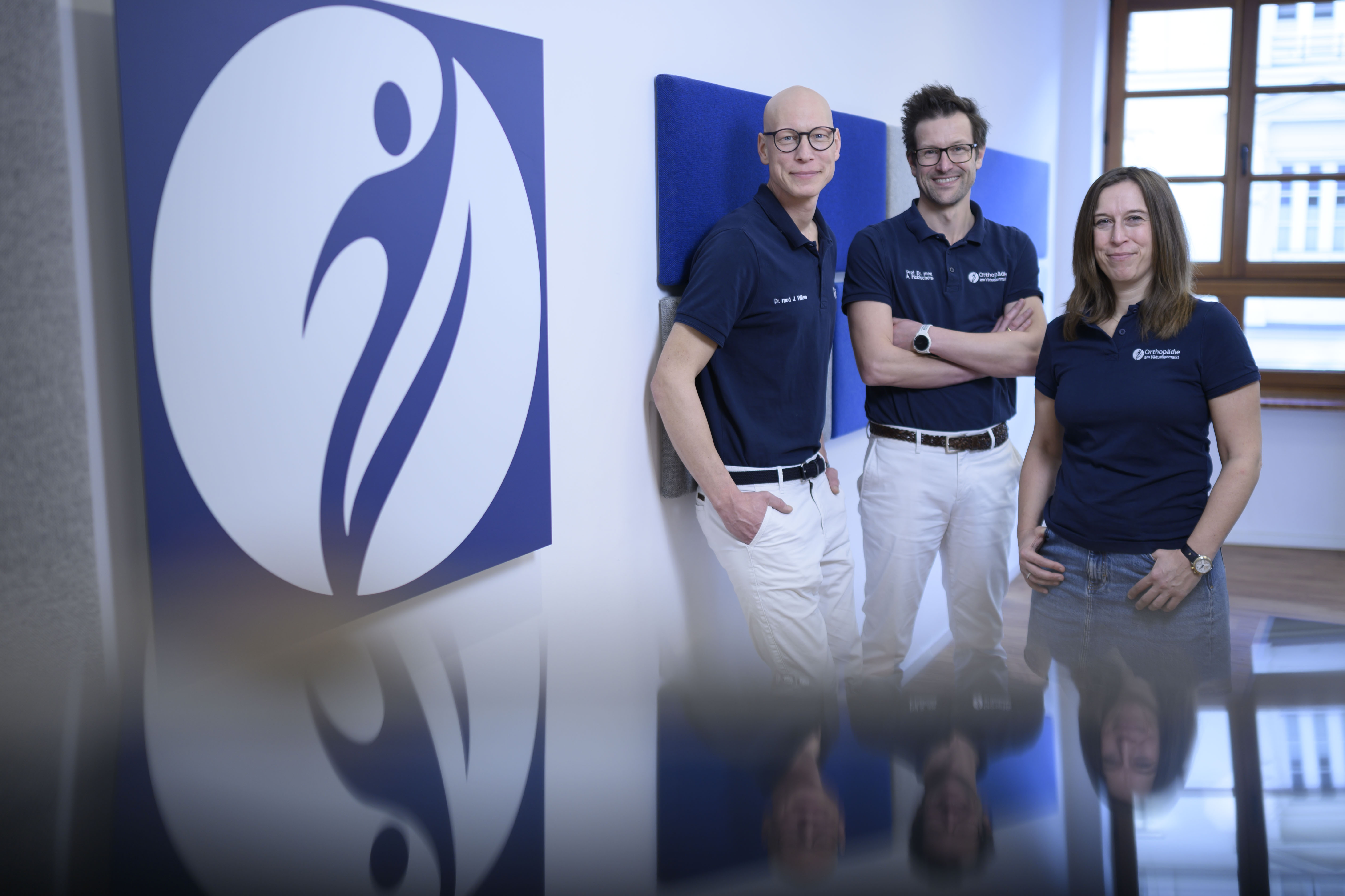 die Ärzte des Praxisteams vor dem Praxislogo